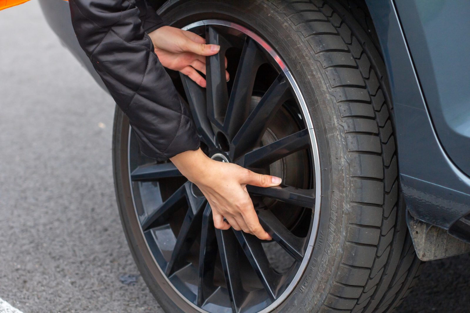 Woman is changing a wheel in broken car on the road. Closeup womans hand on the wheel of a vehicle